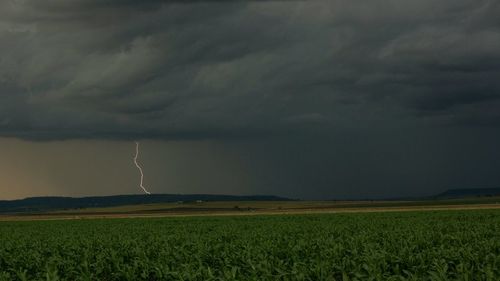 Scenic view of field against storm clouds