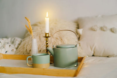 Cup of tea and teapot on a serving tray on a bed.