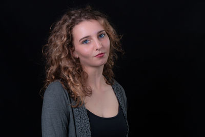 Portrait of teenage girl against black background