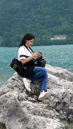 Woman sitting on rock by lake