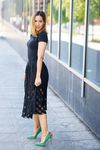 Portrait of young woman standing on footpath