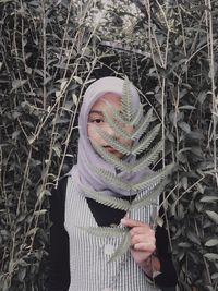 Portrait of woman standing against plants