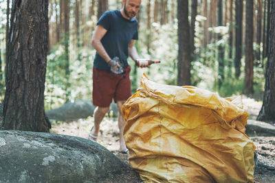 Full length of man standing on tree trunk in forest