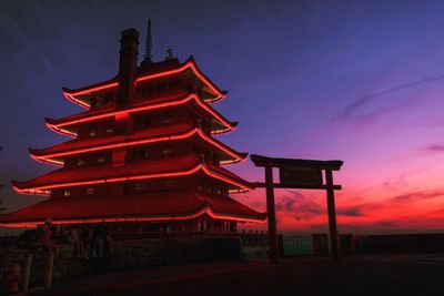 Low angle view of illuminated building against sky at sunset