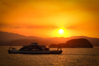 Silhouette of boats sailing in sea during sunset