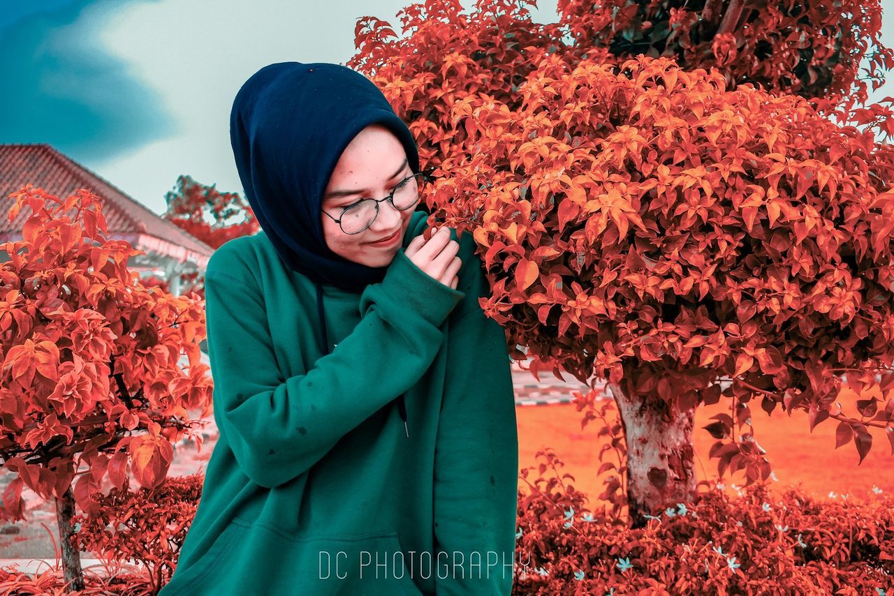 red, autumn, one person, nature, adult, clothing, plant, winter, flower, leaf, spring, young adult, plant part, tree, warm clothing, standing, women, lifestyles, glasses, outdoors, leisure activity, beauty in nature, day, jacket, waist up, eyeglasses, orange color, cold temperature, smiling, portrait, looking, hood, female, coat, scarf, emotion, hood - clothing, hat, land, men, happiness, sky