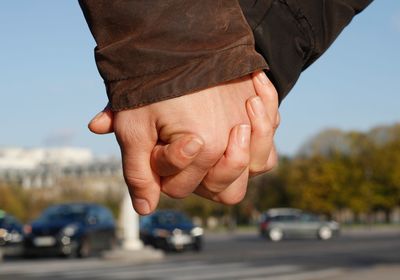 Close-up of couple holding hands on street 