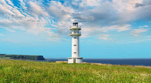 Lighthouse on field against sky