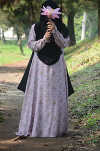 Midsection of woman standing by tree trunk