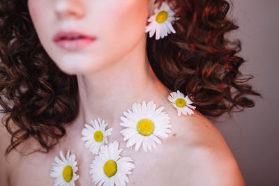 Midsection of young woman wearing flowers and lipstick