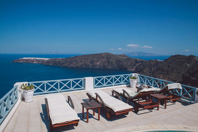 High angle view of lounge chairs on building terrace against sea and blue sky