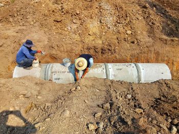 High angle view of workers fixing pipe on land