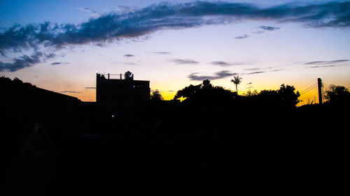 Silhouette buildings against sky at sunset