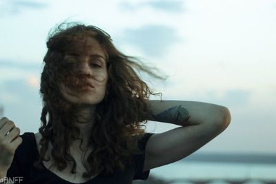 Close-up portrait of young woman against sea