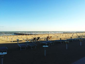 Chairs on beach against clear blue sky