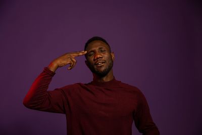 Midsection of man standing against purple background