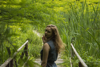 Portrait of young woman standing on boardwalk in forest