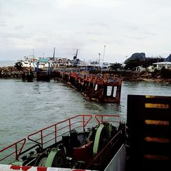 Boats moored at harbor against sky