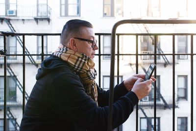 Man using phone against building in city