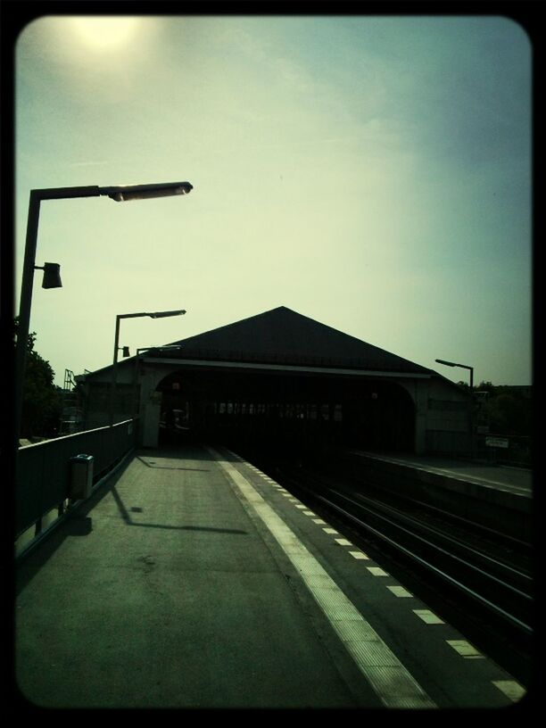 transfer print, railroad track, transportation, built structure, rail transportation, auto post production filter, sky, public transportation, architecture, railroad station, building exterior, railroad station platform, the way forward, diminishing perspective, train - vehicle, street light, outdoors, railing, mode of transport, vanishing point