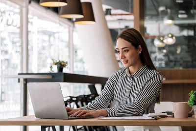 Young woman looking away while sitting in cafe