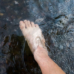 Close up human foot while stand in rapid water stream, relax in shallow creek