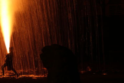 Silhouette man and woman standing against fire at night