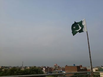 Low angle view of flag amidst buildings against sky