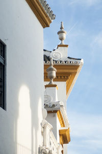 Low angle view of cross amidst buildings against sky