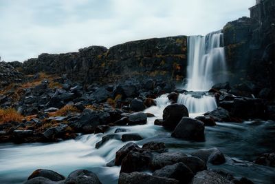 Scenic view of waterfall against rocky mountains