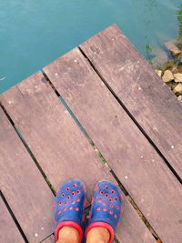 Low section of woman standing on pier at swimming pool