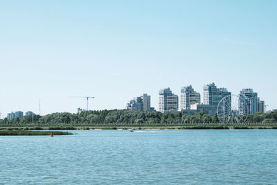 Sea by buildings against clear sky