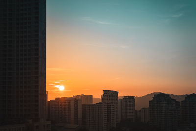 Modern buildings in city against sky during sunset