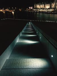 Illuminated walkway in city at night