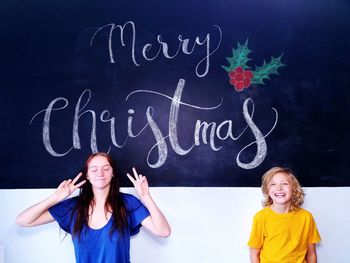 Happy siblings against blackboard during christmas