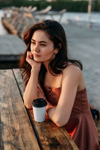 Young woman with coffee while sitting on table