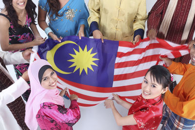 High angle view of friends holding malaysian flag over white background