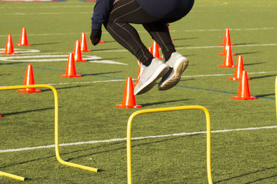 Low section of man jumping over hurdlers