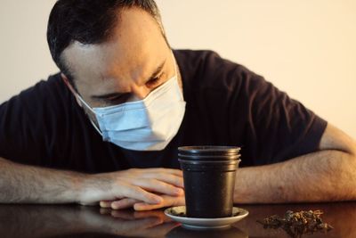 Midsection of man holding coffee cup on table