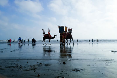 People by sea against sky