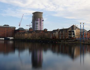 Buildings by river against sky in city