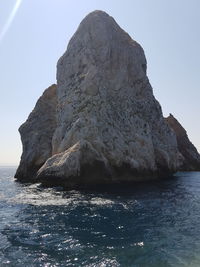 Rock formation in sea against clear sky