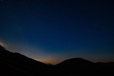 Low angle view of silhouette mountain against sky at night