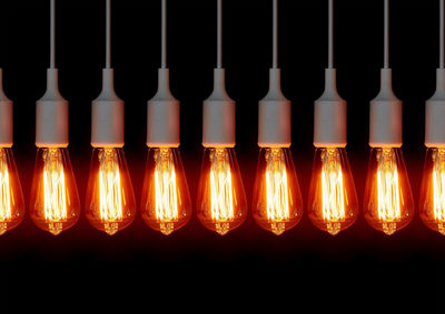 Close-up of illuminated electric bulbs against black background