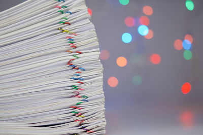 Close-up of paper stacked on table against blurred lights