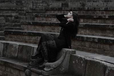 Side view of woman sitting on staircase