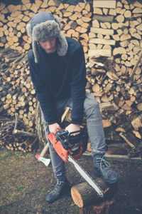 Full length of teenage boy cutting log