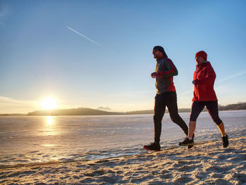 Couple runners running in winter nature. frozen river beach run. copy space.