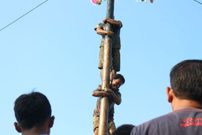 Rear view of people photographing against clear blue sky