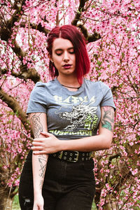 Portrait of young woman standing against trees